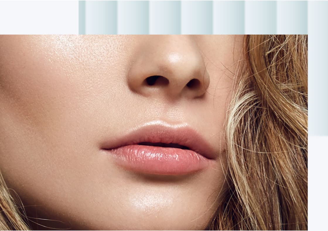 A close-up of a woman's lips and chin with a smooth complexion and soft, natural makeup.