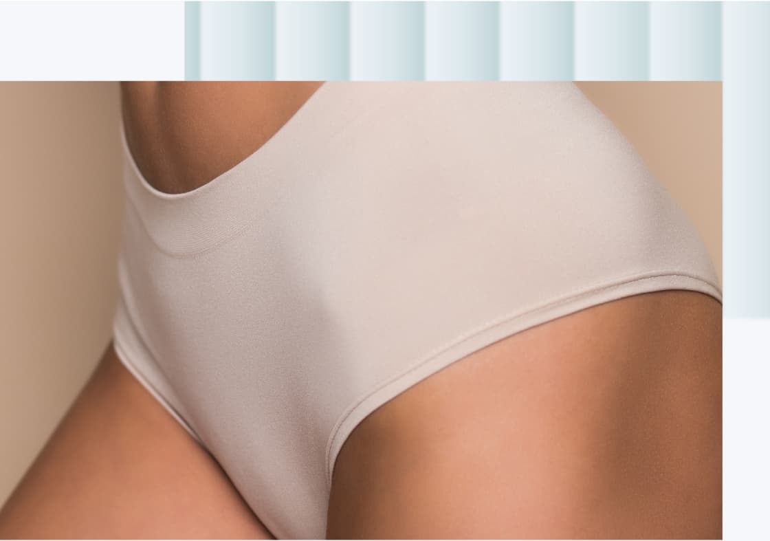 A close-up view of a person's hip and thigh wearing a light beige seamless high-waisted brief.