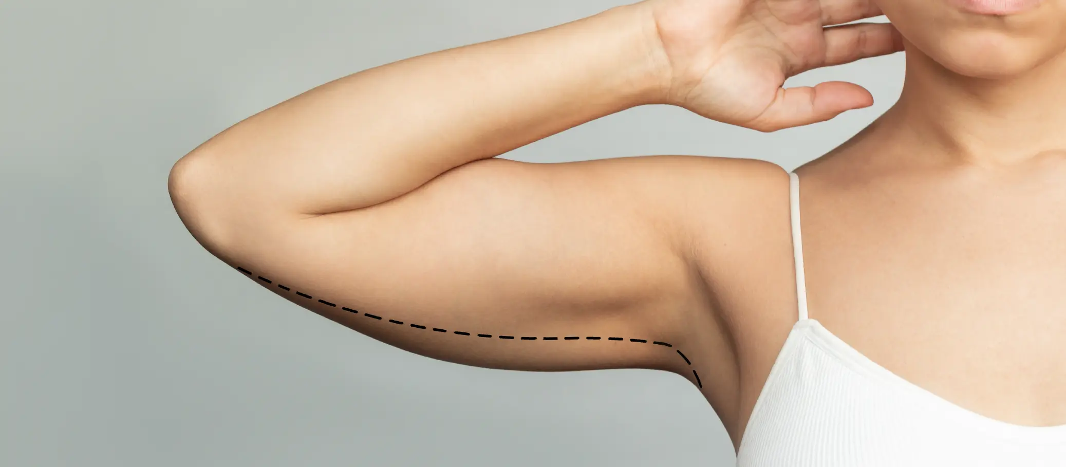 A close-up of a person's arm displaying a defined bicep, with a dashed line extending along the underside of the arm.