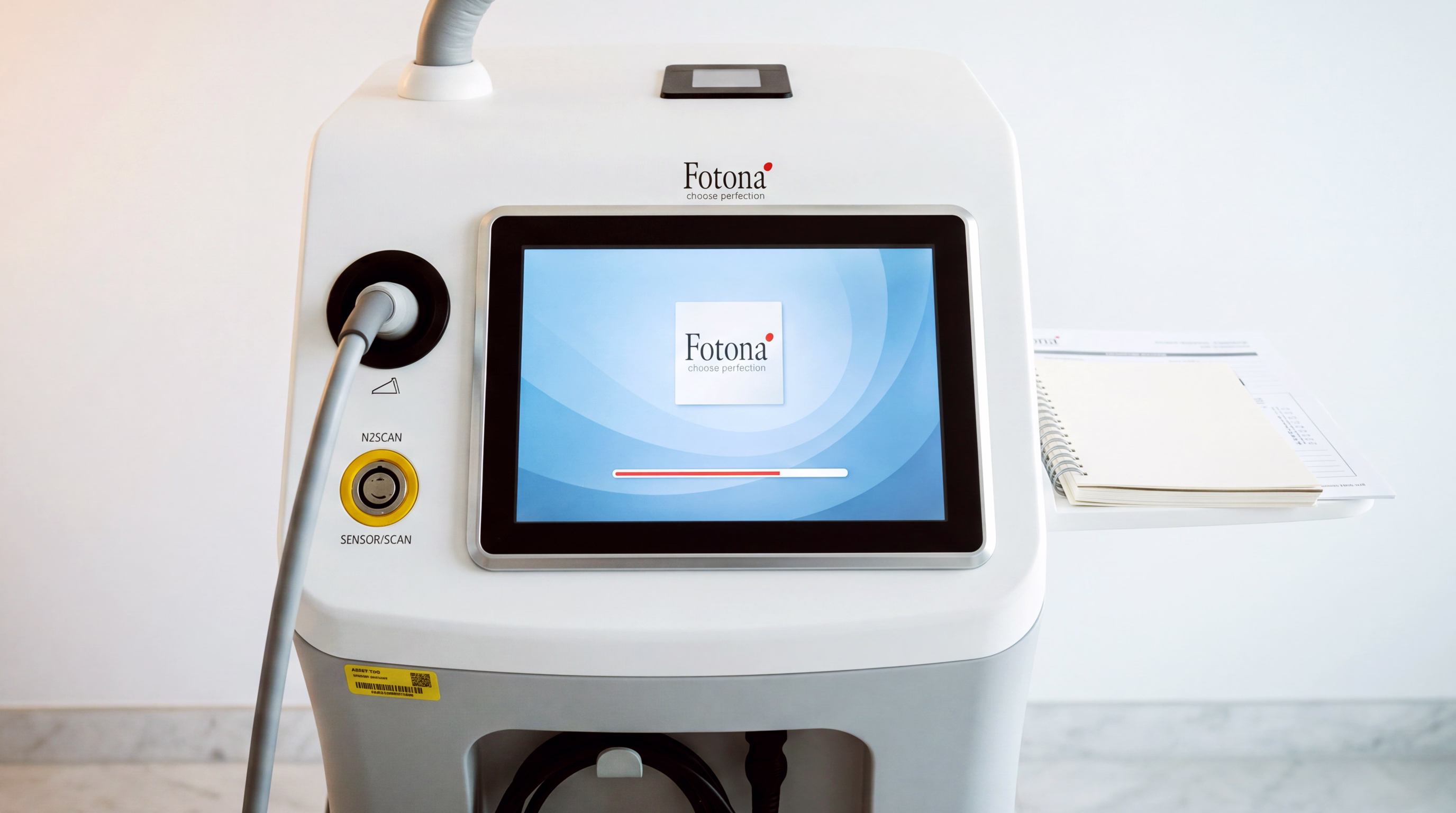 A medical laser device with a central touchscreen displaying the 'Fotona' logo, accompanied by user interface elements such as a power button and a sensor scan button.