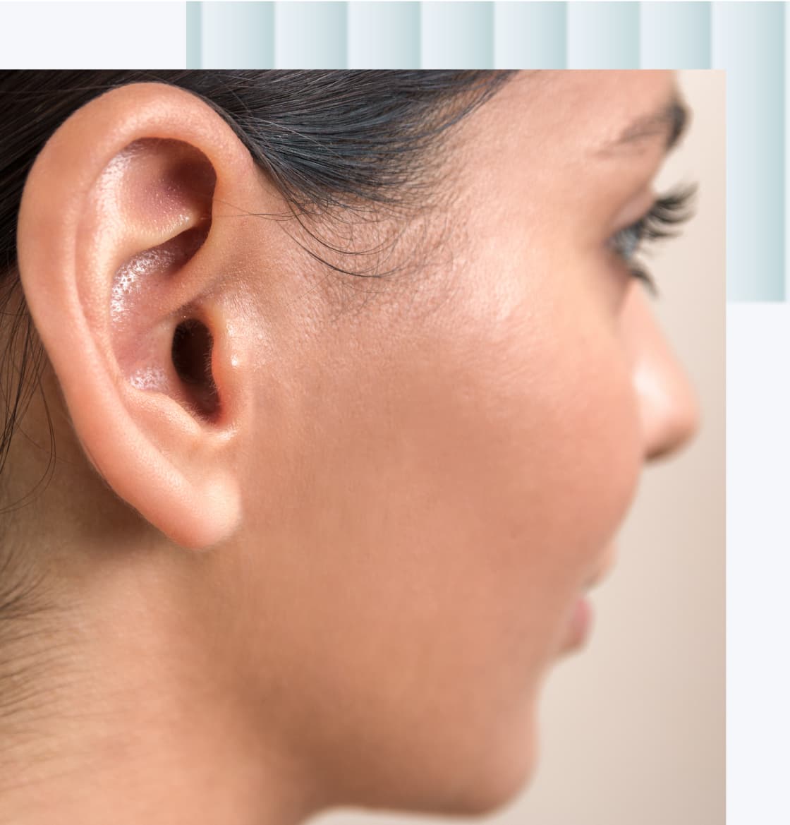 A close-up image of a female ear, focusing on the ear structure and skin texture, with hair partially covering the top of the ear.