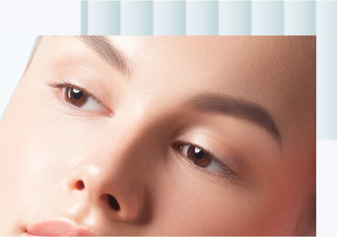 A close-up image of a woman's face featuring smooth skin and well-groomed eyebrows, with a soft expression and natural makeup highlighting her features.