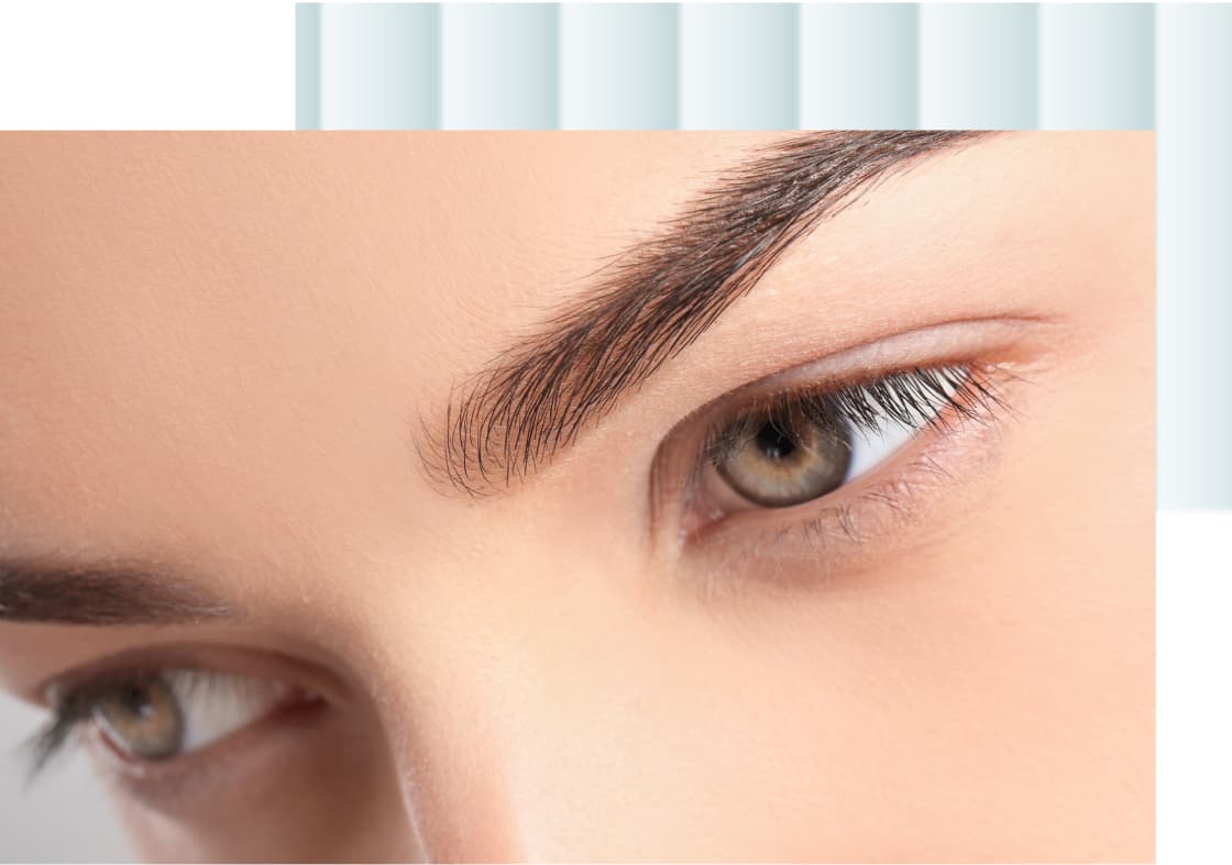 A close-up of a woman's eye, focusing on the eyebrow and eyelashes, with the iris showing shades of brown and green.