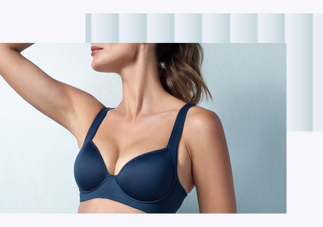 A woman wearing a navy blue bra, posing with one arm raised, showcasing the bra's smooth contours and supportive design.
