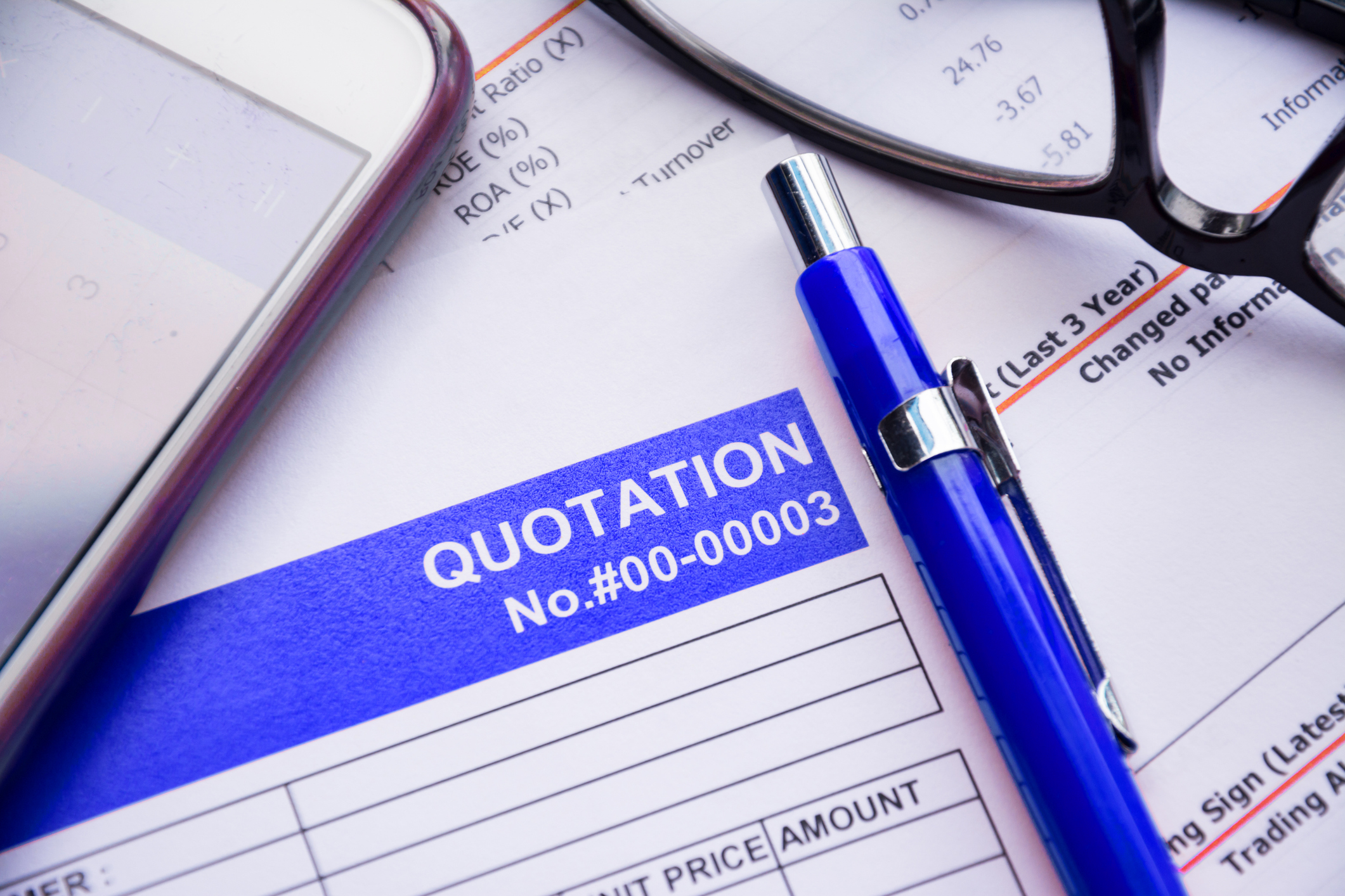 Close-up of a fence quotation form with pen, calculator, and reading glasses on a desk
