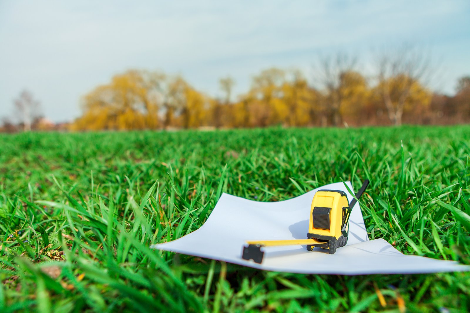 Tape measure and blank paper resting in the grass, ready for property planning