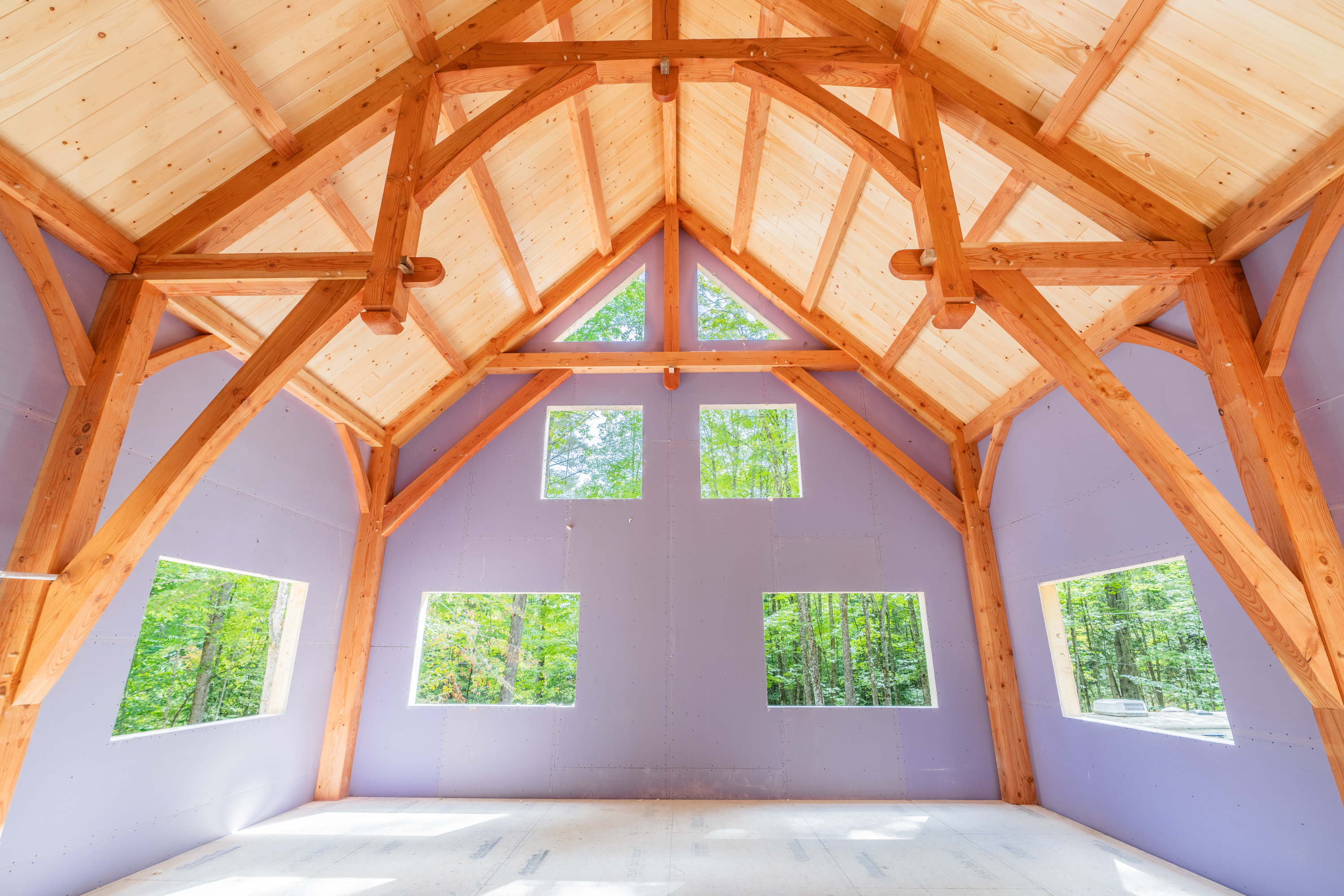 Wooden timber frame interior with large windows overlooking forest