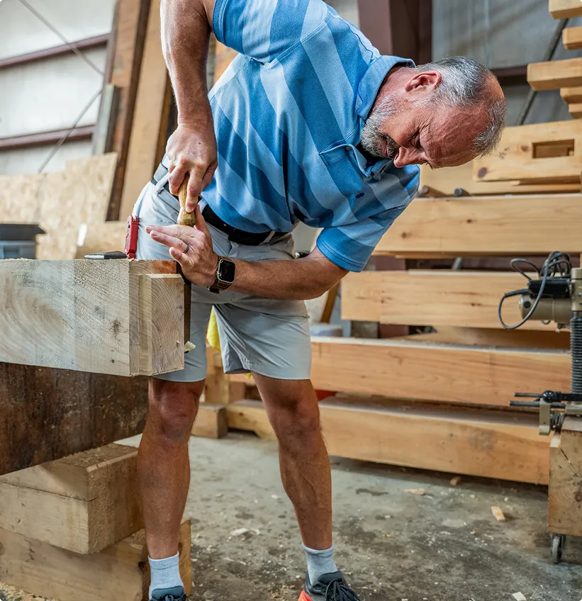Woodworker carefully measuring and marking wood in workshop