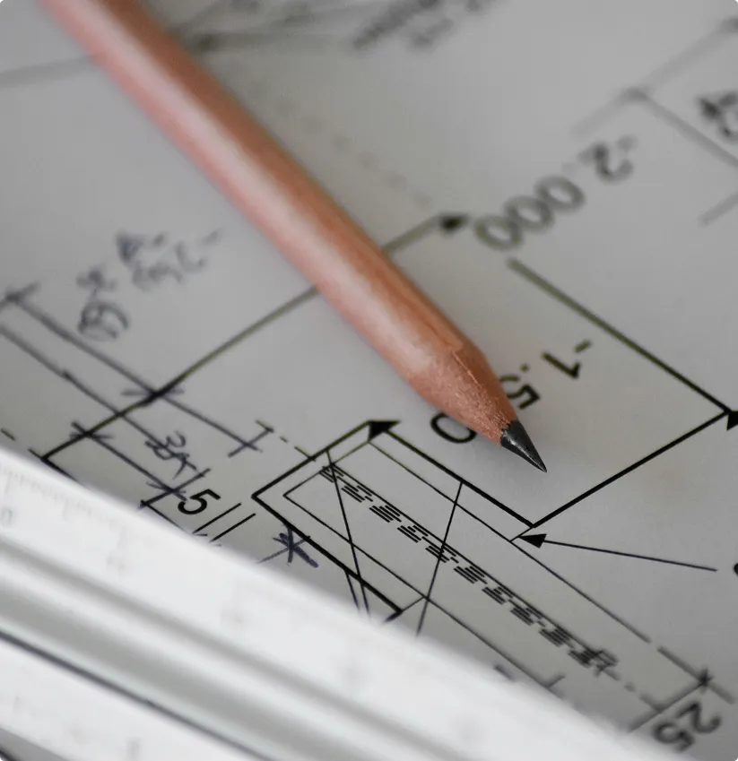 Pencil resting on detailed architectural or engineering blueprint diagram