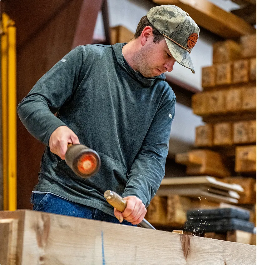 Woodworker using chisel and mallet to shape wood in lumber workshop