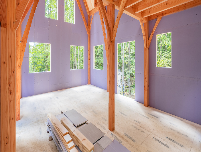 Wooden-framed interior with purple walls and multiple windows showing forest view
