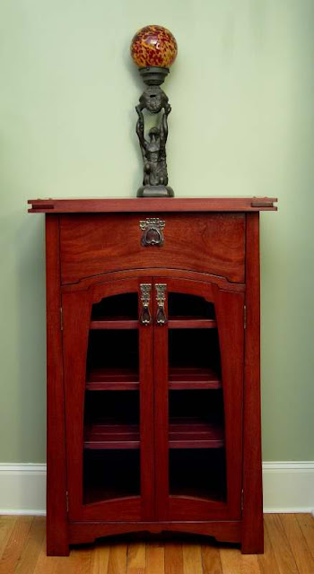 Red wooden cabinet with glass doors and decorative statue with red ball on top.