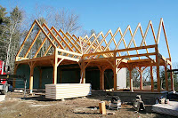 Construction site with wooden frame structure and steel trusses under clear sky