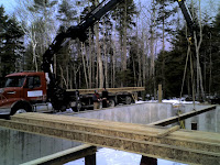 Logging truck loaded with timber in forest clearing near water.