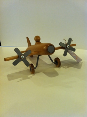Wooden toy airplane with brown fuselage and two propellers on wheels.