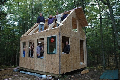 Group of people building wooden structure frame in forest clearing during construction project