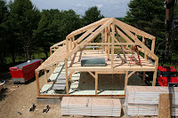 Wooden house frame structure under construction with exposed rafters and trusses