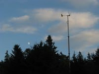 Tall communication tower with trees silhouetted against cloudy sky