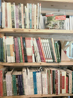 Wooden bookshelf with three shelves filled with books organized by color and size.