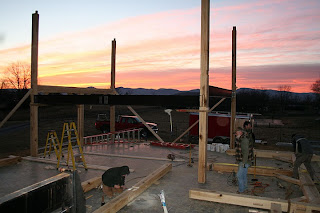 Construction site with wooden posts and structural framework at sunset with pink sky