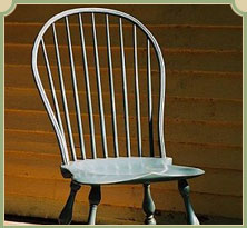 White spindle back chair with wooden legs against brown wooden wall background.
