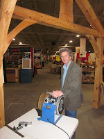 Man standing in warehouse with wooden beams examining blue equipment on table