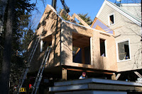 House construction with wooden framing and white exterior walls under clear blue sky