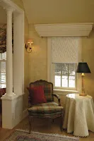 A cozy reading nook with burgundy armchair, window with cream curtains, and table lamp