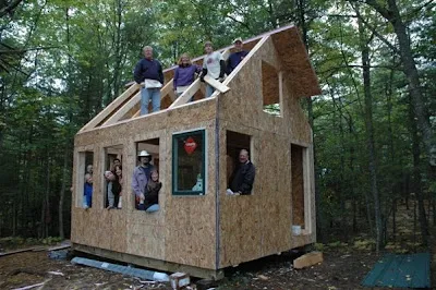 Group of people building wooden structure frame in forest clearing during construction project