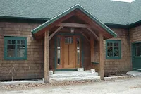 Brick church building with wooden arched entry door and green shutters