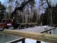 Logging truck loaded with timber in forest clearing near water.