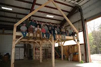 Interior wooden frame structure under construction with people on platform