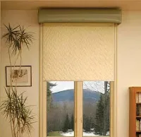 Beige roller shade partially covering two-pane window with mountain views visible