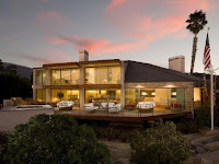 Modern residential home illuminated at dusk with desert landscaping and palm tree