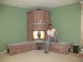 Brick fireplace with glowing fire in mint green room under construction