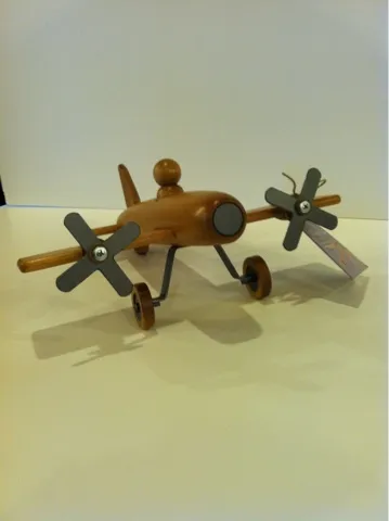 Wooden toy airplane with brown fuselage and two propellers on wheels.