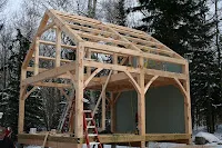 Wooden timber frame structure under construction in snowy forest setting