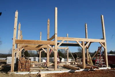 Wooden timber frame structure under construction against clear blue sky