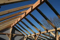 Wooden beam construction against blue sky during building frame assembly