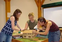 Four people working together on a wooden construction project indoors