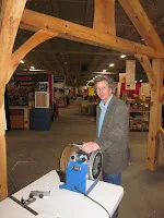 Man standing in warehouse with wooden beams examining blue equipment on table