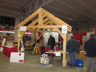 Wooden structure with red wall at indoor market or craft fair with shoppers.