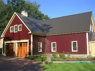 Red barn with dark metal roof and yellow trim doors sunny day