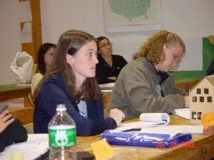 Children sitting at table working on classroom learning activity with materials and supplies