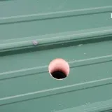 Pink sphere resting on green parallel lined surface or roof