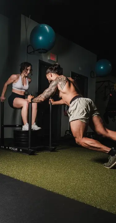 A man and woman exercising together in a gym at CrossFit 812 in Vincennes, IN, showcasing teamwork and fitness.