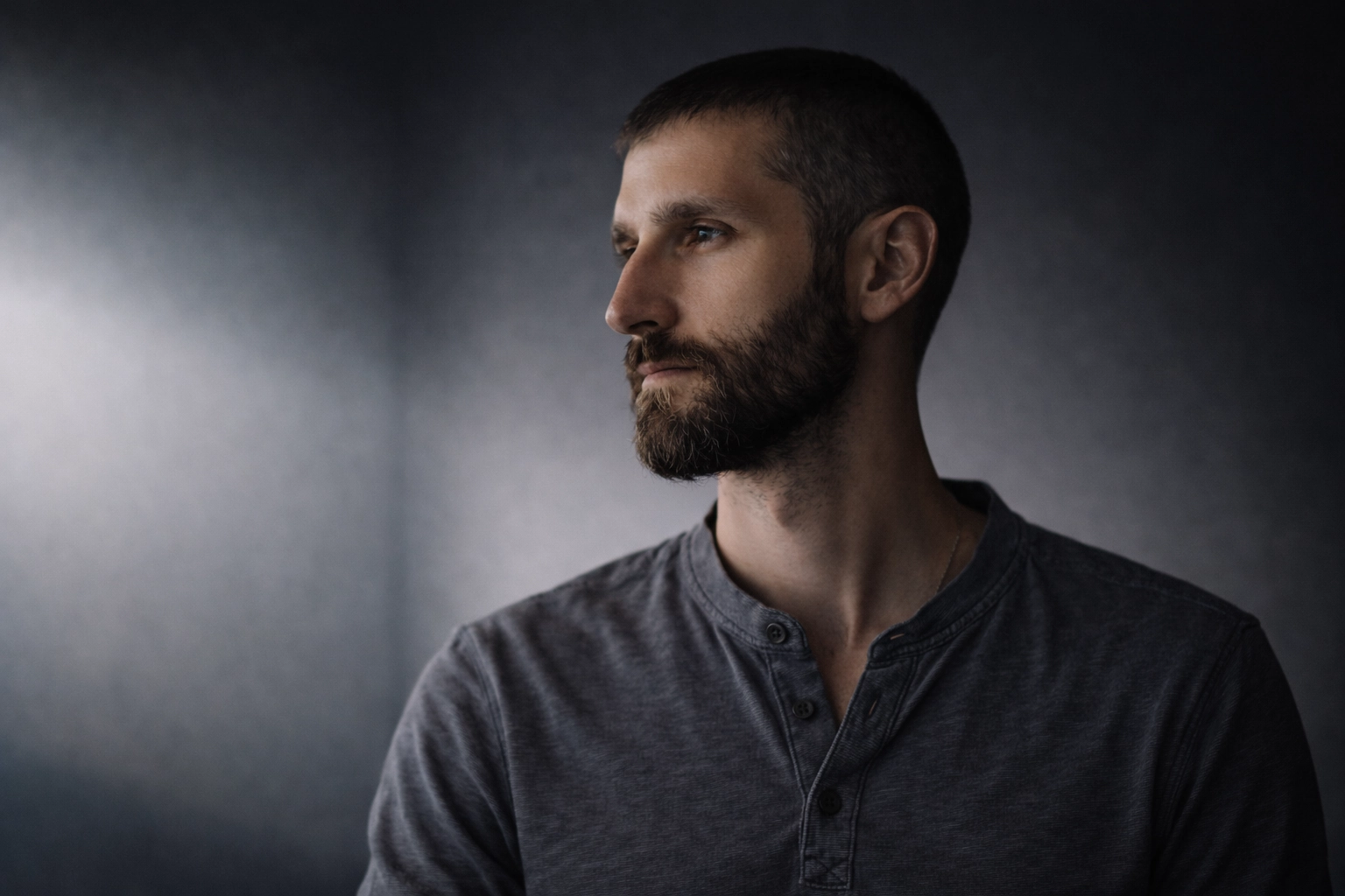 Portrait of Stephan Singh Ryatt, founder and AI product architect of Ākāśa Systems, standing against a dark gradient background with soft side lighting. He looks off to the side with a calm and introspective expression.