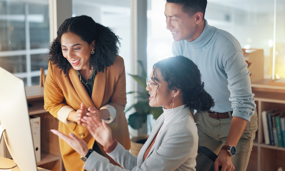 Business, people and celebrate for teamwork success, support and collaboration with computer in office. Celebration, man and women happy together with pride or congratulations for work feedback