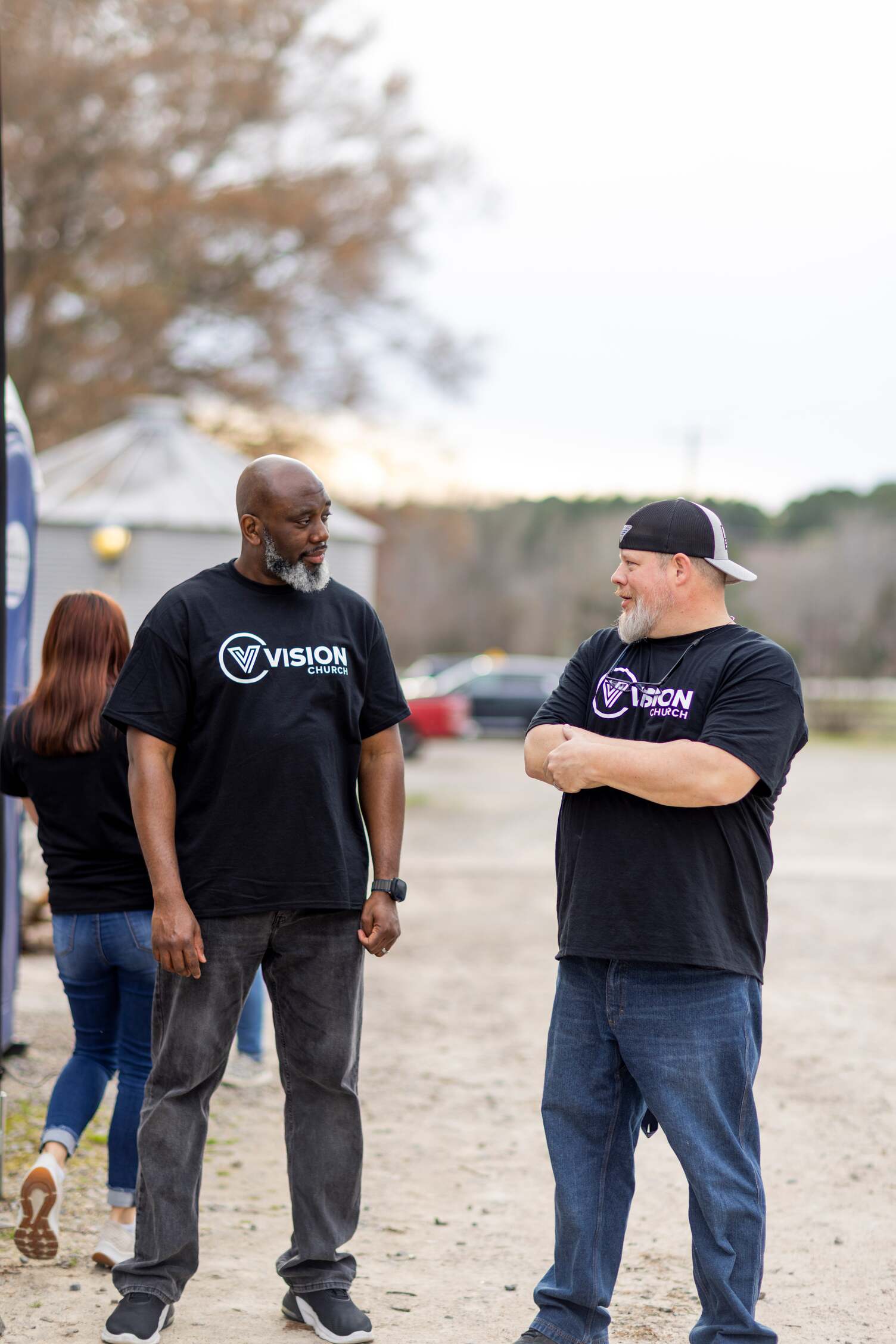 Two men wearing Vision Church shirts, talking to each other outside