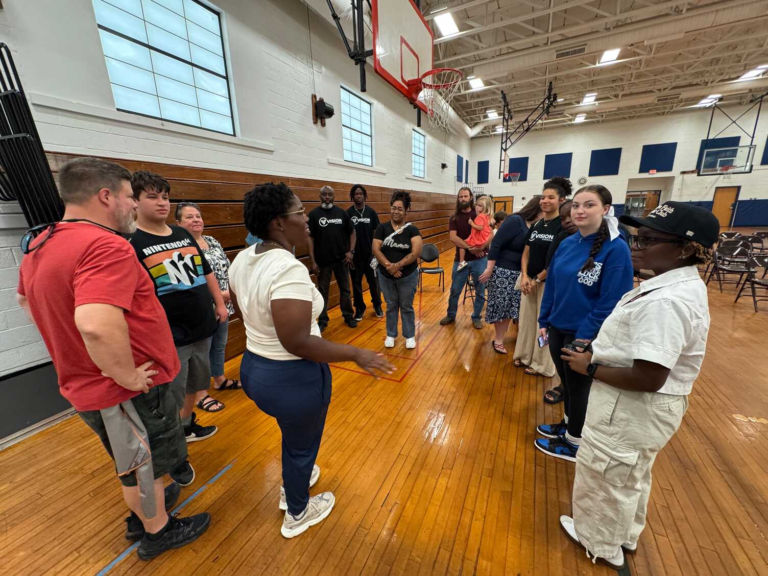 A group of people in a circle in a gymnasium.
